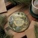 A decorative ornament featuring a scenic image of Patapsco Valley State Park, Maryland, with a couple walking along a path surrounded by pine trees.