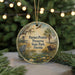A circular ornament with a painting of a bird, a palm tree, and a buffalo, along with the text "Paynes Prairie Preserve State Park, Florida" on it, is displayed in front of a blurred background with Christmas lights.