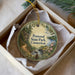 A round ornament with a scenic landscape of Penwood State Park, Connecticut, hanging from a string.