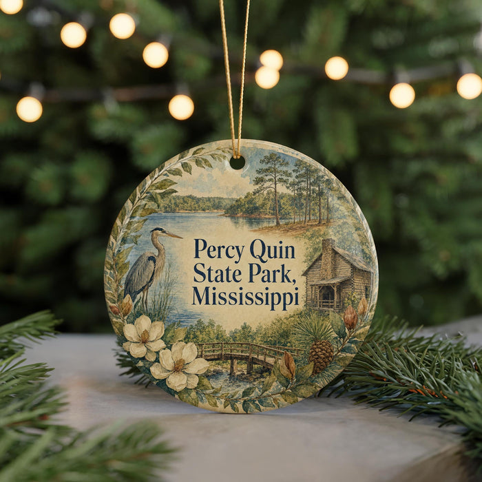 A round ornament with a painting of a park scene, featuring a bird, flowers, and a cabin, hanging from a string.