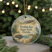A round ornament with a beach scene and a bird, hanging on a string.