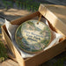 A decorative ornament in a box, featuring a scenic landscape with a river, trees, and a building, likely representing the state park in Illinois.