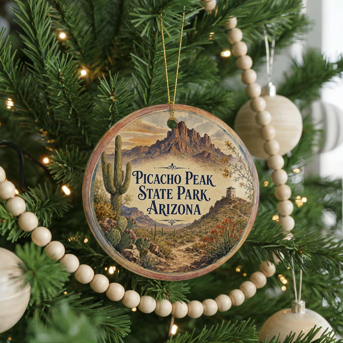 A round ornament hanging on a Christmas tree, featuring a desert landscape with mountains and cacti.