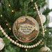 A round ornament hanging on a Christmas tree, featuring a desert landscape with mountains and cacti.