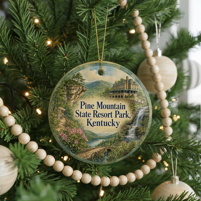 A round ornament hanging on a Christmas tree, featuring a scenic image of Pine Mountain State Resort Park, Kentucky.