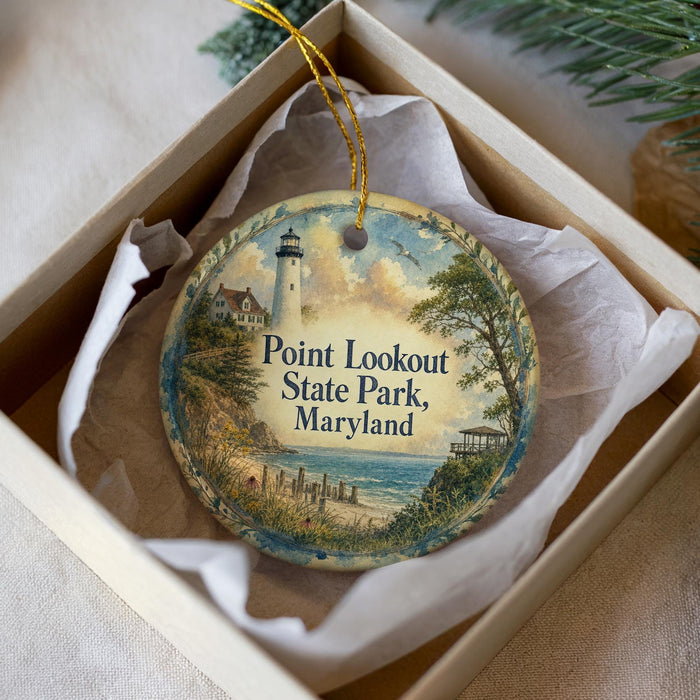A decorative ornament in a box, featuring a lighthouse and a scenic landscape, with the text "Point Lookout State Park, Maryland" printed on it.