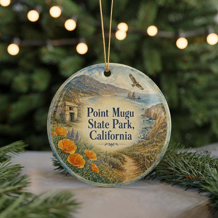 A round ornament with a scenic landscape of Point Mugu State Park, California, featuring a winding path, mountains, and a bird in flight.