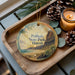 A wooden tray with a decorative ornament featuring a scenic image of Polihale State Park in Hawaii, accompanied by pine cones and a lit candle.