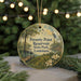 A round ornament with a painting of a park scene, featuring a bird, trees, and a pond, hanging from a string.