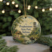 A round ornament with a painting of a scenic landscape, including a river, a lighthouse, and a small hut, surrounded by greenery and trees.