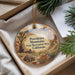 A decorative ornament with a scenic mountain landscape and desert elements, hanging from a string.