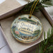 A decorative ornament in a box, featuring a scenic image of Quaddick State Park in Connecticut.