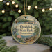 A round ornament with a scenic illustration of Quaddick State Park, Connecticut, featuring a bird, a bridge, and a river.