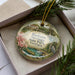 A decorative ornament in a box, featuring a scenic image of Radium Springs State Park in Georgia.