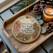A wooden tray with a decorative ornament featuring a scenic image of Red Rock Canyon State Park, California, and pine cones.