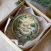 A round ornament with a scenic landscape of Reid State Park, Maine, displayed in a box with a white tissue paper lining.