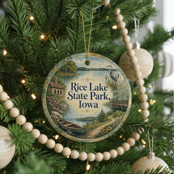 A round ornament hanging on a Christmas tree, featuring a scenic image of Rice Lake State Park, Iowa.