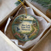 A decorative ornament in a box, featuring a scenic landscape with a lake, waterfall, and surrounding nature.