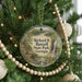 A round ornament hanging on a Christmas tree, featuring a scenic image of a lake and mountains with a waterfall.