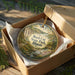 A decorative ornament in a box, featuring a scenic landscape with a river and lush greenery, with the text "Rock Cut State Park, Illinois" prominently displayed.