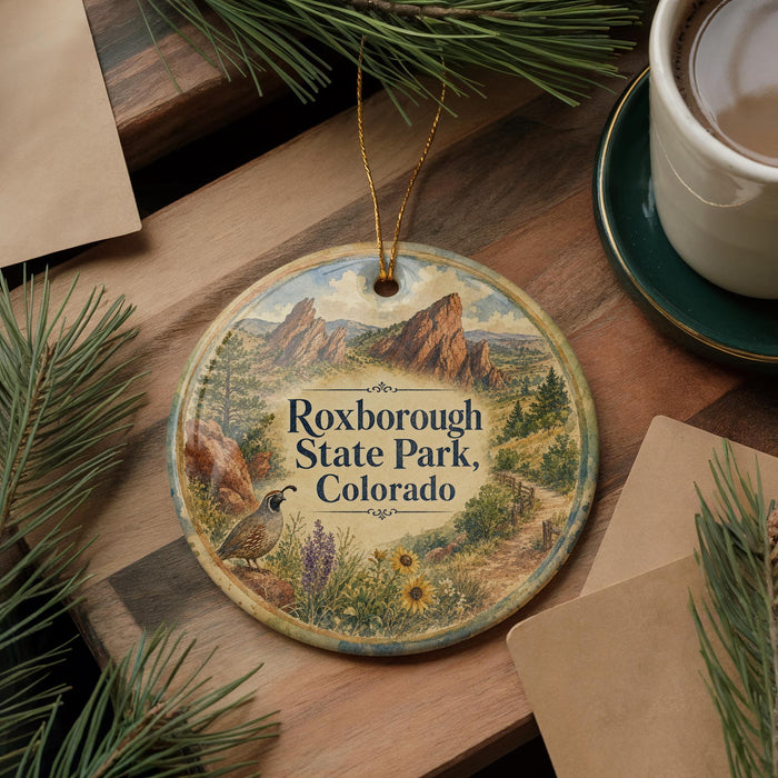 A decorative ornament featuring a scenic image of Roxborough State Park in Colorado, with pine branches and a cup of coffee nearby.