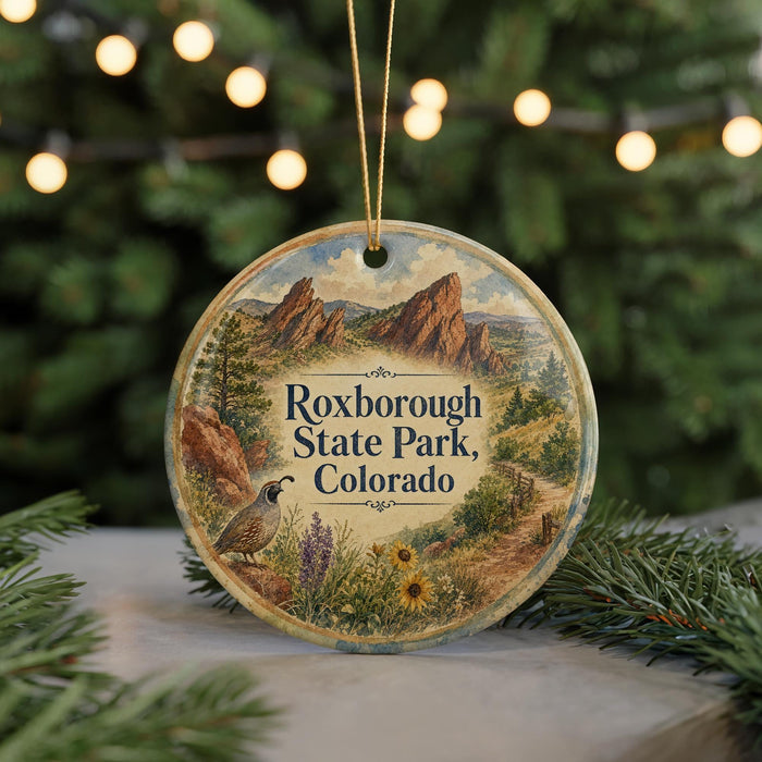 A round ornament with a scenic image of the Rocky Mountains and a bird, hanging on a string.