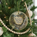 A round ornament hanging on a Christmas tree, featuring a scenic landscape with a waterfall and pine trees.