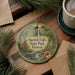 A decorative ornament with the text "Sacred Falls State Park, Hawaii" is displayed on a wooden surface, surrounded by pine branches and a cup of coffee.