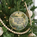 A round ornament hanging on a Christmas tree, featuring a scenic image of ducks and a lake surrounded by trees.