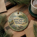 A decorative ornament featuring a scenic image of Seven Lakes State Park, Michigan, with pine branches and a cup of coffee nearby.