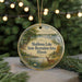 A round ornament with a scenic landscape featuring a lake, trees, and wildlife, including a deer, is displayed in front of a blurred background with Christmas lights.
