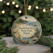 A round ornament with a scenic landscape of a beach, mountains, and a seagull, hanging from a string.