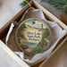 A round ornament in a box, depicting a scenic view of Silver Lake State Park in Michigan.