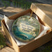 A decorative ornament in a box, featuring a manatee and surrounded by greenery, with text that reads "Silver Springs State Park, Florida".