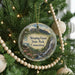 A round ornament hanging on a Christmas tree, featuring a scenic landscape with a waterfall and mountains.