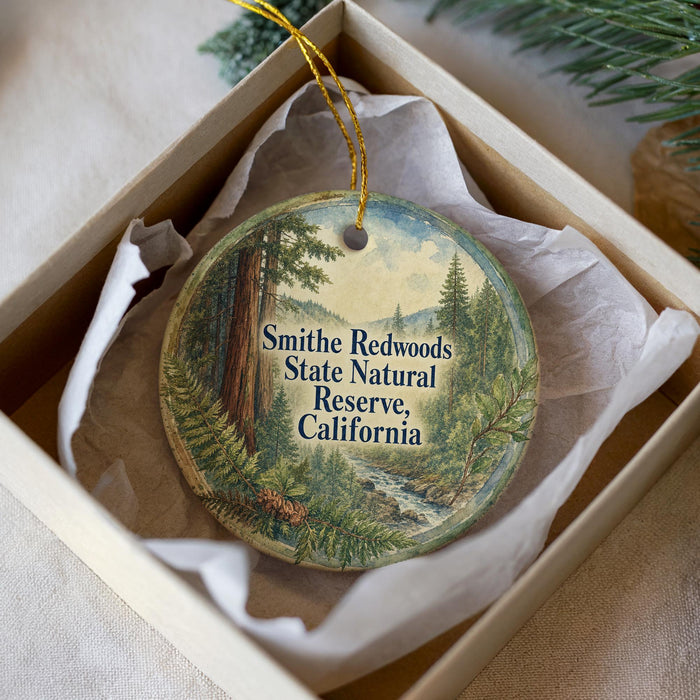 A round ornament with a forest scene and text, placed in a box with a white tissue paper lining.