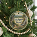 A round ornament hanging on a Christmas tree, featuring a scenic landscape with a waterfall and a castle in the distance.