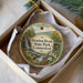 A decorative ornament in a box, featuring a scenic landscape with a waterfall and flowers, with the text "Stratton Brook State Park, Connecticut" printed on it.