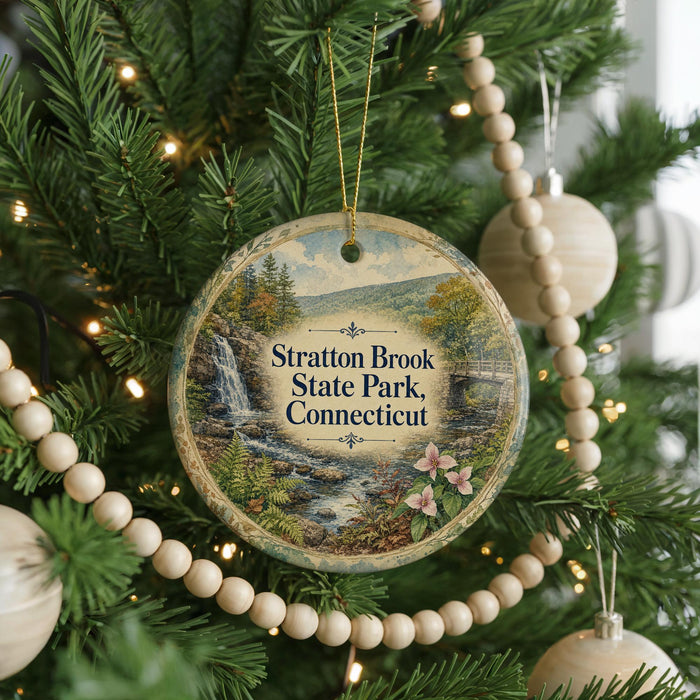 A round ornament hanging on a Christmas tree, featuring a scenic image of Stratton Brook State Park in Connecticut.