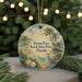 A round ornament with a beach scene and a bird, hanging on a string.