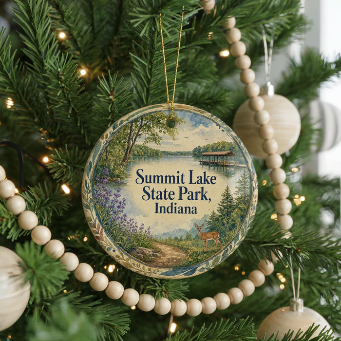 A round ornament hanging on a Christmas tree, featuring a scenic landscape with a lake, trees, and a deer.