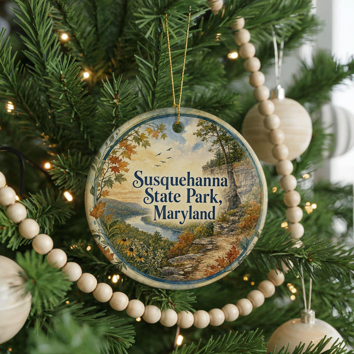 A round ornament hanging on a Christmas tree, featuring a scenic landscape with a river and mountains.
