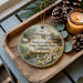 A decorative ornament featuring a scenic image of Sutter's Fort State Historic Park, California, with a candle and pine cones on a wooden tray.