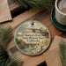 A decorative ornament with a painting of a historical building and a river, hanging on a wooden surface.