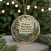 A round ornament with a scenic mountain landscape and a tower, hanging on a string.