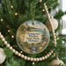 A round ornament hanging on a Christmas tree, featuring a lighthouse and a scenic landscape.
