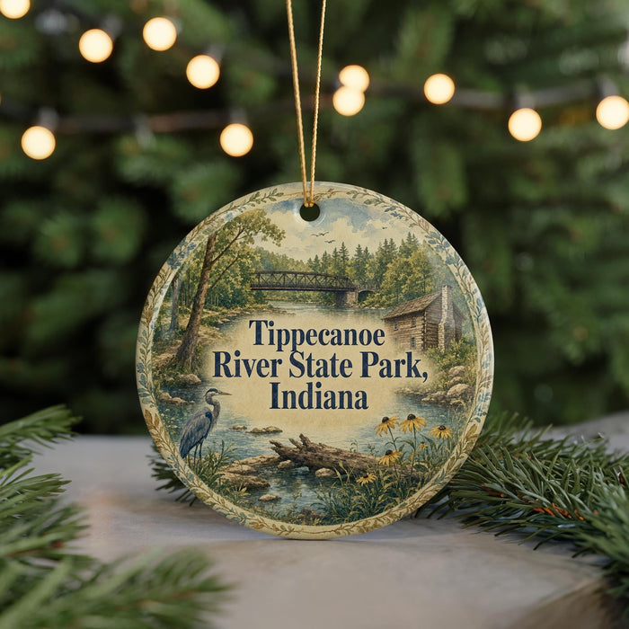A decorative ornament featuring a scenic image of Tippecanoe River State Park, Indiana, with a bird and a bridge in the background.