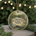 A decorative ornament featuring a scenic image of Tippecanoe River State Park, Indiana, with a bird and a bridge in the background.