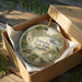 A decorative ornament in a box, featuring a scenic image of Tomoka State Park, Florida.