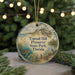 A round ornament with a beach scene and a bird, hanging on a string.
